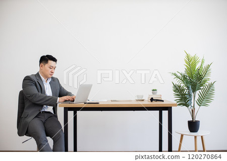 Asian businessman working on laptop in modern office space 120270864