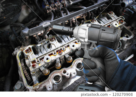 A mechanic use a cordless impact wrench to repairing a car engine A mechanic use a cordless impact wrench to repairing a car engine 120270908