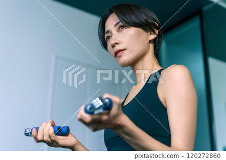 Woman training her arms with hand grips at the gym 120272860