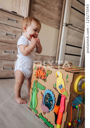 Child plays with busy board. Educational toys for children, wooden game panel 120273043