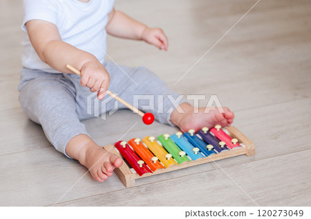 little girl in white bodysuit sitting on floor and playing with colorful toy little girl in white bodysuit sitting on floor and playing with colorful toy 120273049