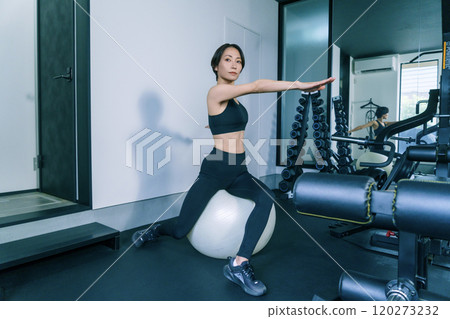A woman training on a balance ball at the gym 120273232