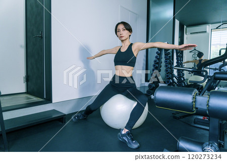 A woman training on a balance ball at the gym 120273234