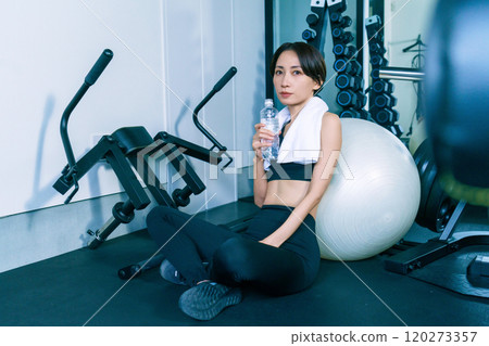 一位女士在健身房靠著平衡球休息 120273357