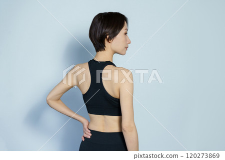 A woman wearing gym wear with her back turned against a white background 120273869