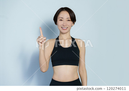 A woman in gym wear posing in the number 1 position on a white background 120274011