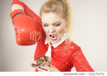 Woman fighting off bad food, boxing chocolate cake 120274752