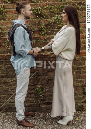 A cheerful multiracial couple in Warsaw, Poland, enjoys their time together. Couple against a rustic red brick background. Woman and man at the beautiful the brick wall background. A brick wall. A cheerful multiracial couple in Warsaw, Poland, enjoys their time together. Couple against a rustic red brick background. Woman and man at the beautiful the brick wall background. A brick wall. 120275175