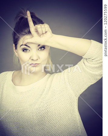 Woman showing loser gesture with L on forehead Woman showing loser gesture with L on forehead 120275599