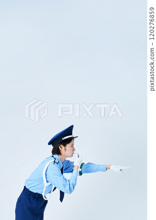 A female security guard blowing a whistle and pointing 120276859