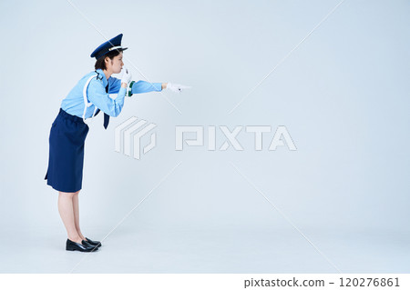 A female security guard blowing a whistle and pointing 120276861