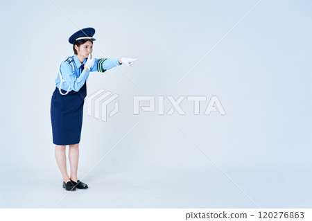 A female security guard blowing a whistle and pointing 120276863