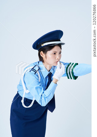 A female security guard blowing a whistle and pointing 120276866