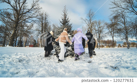 School friends run around the spruce tree holding hands. Christmas concept. 120277631