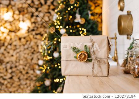 Wrapped gift with a pine tree and orange ornament on a wooden table Wrapped gift with a pine tree and orange ornament on a wooden table 120278194