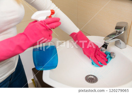 A woman is cleaning the bathroom sink with spray cleaner for hygiene and freshness A woman is cleaning the bathroom sink with spray cleaner for hygiene and freshness 120279065