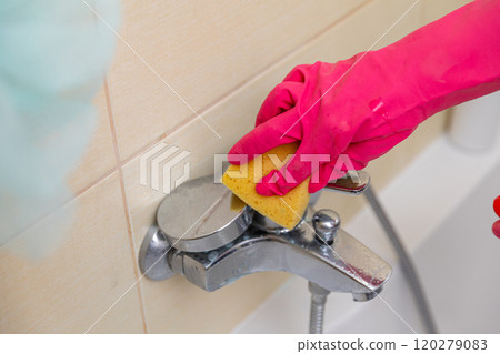 Cleaning your bathroom faucet with a sponge and gloves ensures hygiene and appearance Cleaning your bathroom faucet with a sponge and gloves ensures hygiene and appearance 120279083