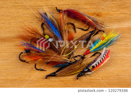 Pile of Traditional Salmon Fishing Flies on a Wooden Surface 120279386