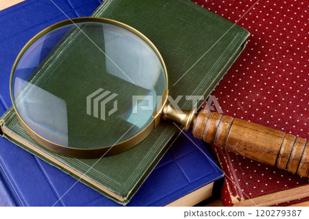 Vintage Magnifying Glass with Old Books on a Wooden Table Vintage Magnifying Glass with Old Books on a Wooden Table 120279387
