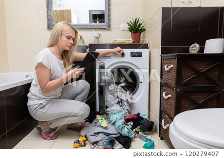 A Frustrated Woman Struggling with a Huge Laundry Mess Right Next to the Washing Machine 120279407