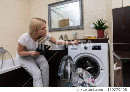 A Modern Laundry Room featuring a Woman Operating a Washing Machine with efficiency and style 120279408