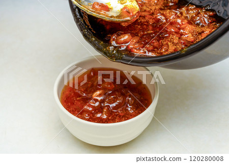 Filling a bowl with freshly brewed sea buckthorn jam from a saucepan. Filling a bowl with freshly brewed sea buckthorn jam from a saucepan. 120280008