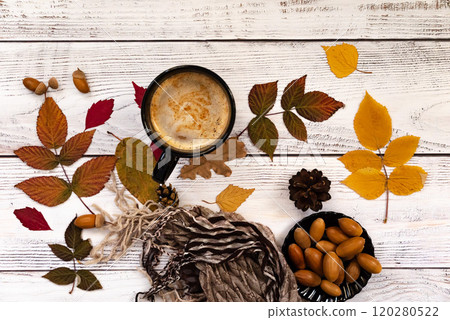 Autumn, fall leaves, hot steaming cup of coffee and a warm scarf on wooden table background. Seasonal, morning coffee, Sunday relaxing and still life concept. Autumn, fall leaves, hot steaming cup of coffee and a warm scarf on wooden table background. Seasonal, morning coffee, Sunday relaxing and still life concept. 120280522