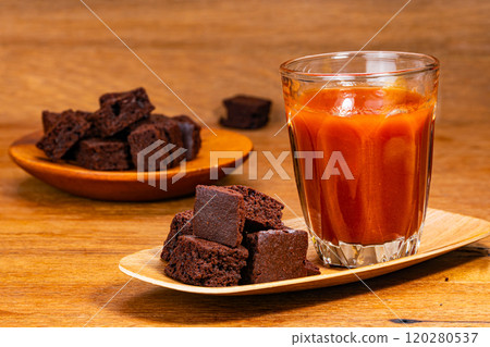 Closeup view pile of crispy brownie chocolate cube and a glass of tomato juice. Closeup view pile of crispy brownie chocolate cube and a glass of tomato juice. 120280537
