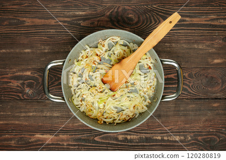 Sizzling sauteed onions and garlic in a pan on a wooden kitchen table during meal preparation Sizzling sauteed onions and garlic in a pan on a wooden kitchen table during meal preparation 120280819