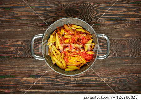 Freshly cooked potatoes mixed with ripe tomatoes and bell peppers are simmering together in a pot 120280823