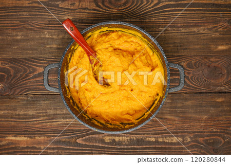 Creamy mashed pumpkin in a pot with a wooden spoon on a rustic wooden table Creamy mashed pumpkin in a pot with a wooden spoon on a rustic wooden table 120280844