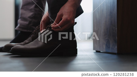 Young man put on his brown leather chukka boots indoor 120281238