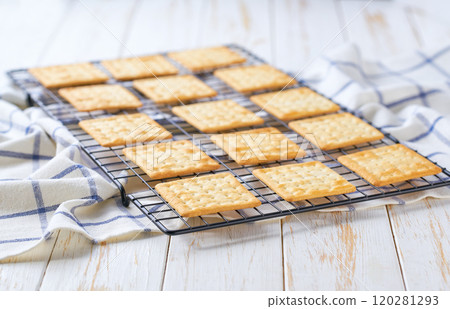 Traditional dry biscuits are cooling after baking on a rack on a white table, selective focus. 120281293