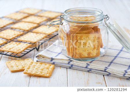 Wheat biscuits in a jar, on a light kitchen table, with copy space for text. Glass jar with dry biscuits on a white table. 120281294
