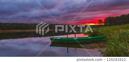A Serene Sunset Over Calm Waters Featuring a Charming Green Boat Floating Gracefully. Birstonas, Lithuania 120281622