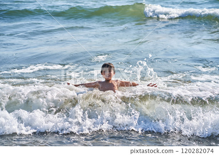 An 11 year old boy in having fun in the sea waves. 120282074