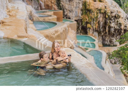 Mother with her toddler and teenage sons bathing in the hot springs of Grutas Tolantongo, Mexico. Family adventure, relaxation, and natural wellness concept 120282107