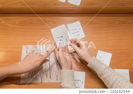 the doctor points to the sound card. hands on the table holding exercise cards for the sounds of words 120282544