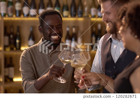 African American sommelier smiling widely while clinking glasses with his biracial colleagues and celebrating successful degustation 120282671