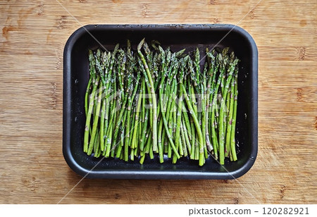 Fresh raw asparagus arranged in baking tray, lightly seasoned with salt, ready for cooking Fresh raw asparagus arranged in baking tray, lightly seasoned with salt, ready for cooking 120282921