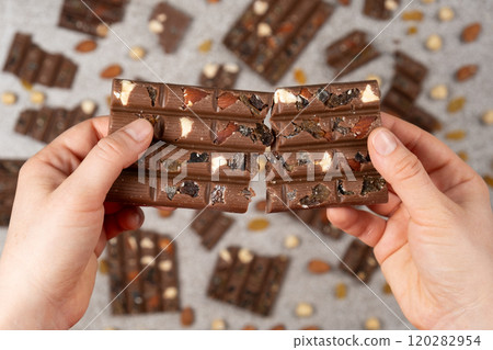 Broken chocolate bar in hands close-up view from above. Broken chocolate bar in hands close-up view from above. 120282954