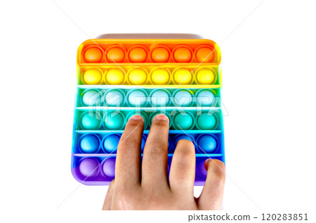 Hand of a little girl touching a colorful Pop it Fidget Toy sensory stress relief toy, on white background. Copy space 120283851