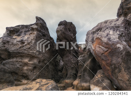 The rough shapes and textures of ancient rocks under a gray sky showcase the harsh and majestic beauty of nature 120284341