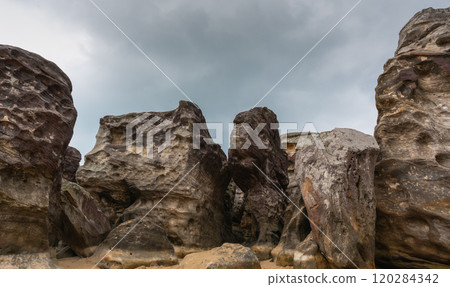Stone monoliths and rock formations against a cloudy sky convey the grandeur and power of nature 120284342