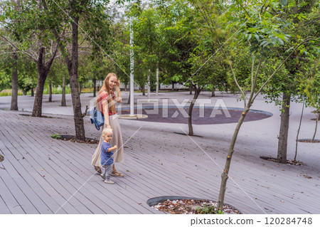 Mother with her toddler son walking in the park. Family bonding, outdoor exploration, and parenting concept 120284748