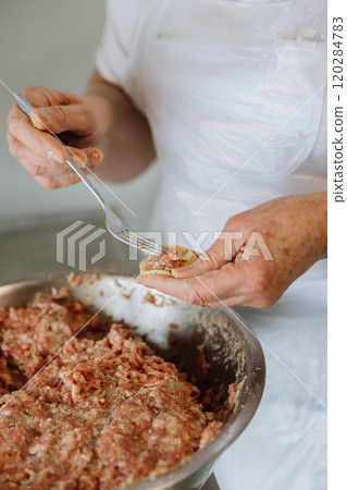 Filling a handmade dumpling with minced meat using a fork, traditional cooking process close up Filling a handmade dumpling with minced meat using a fork, traditional cooking process close up 120284783