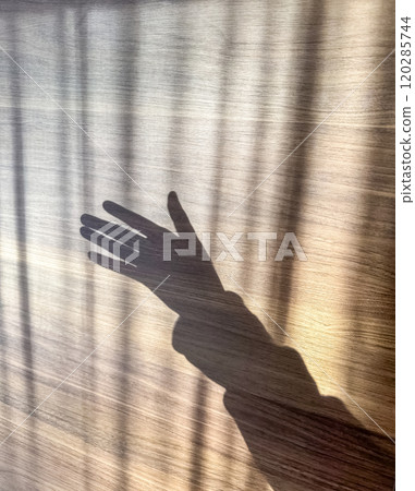 A menacing hand shadow on wooden background . High quality photo 120285744