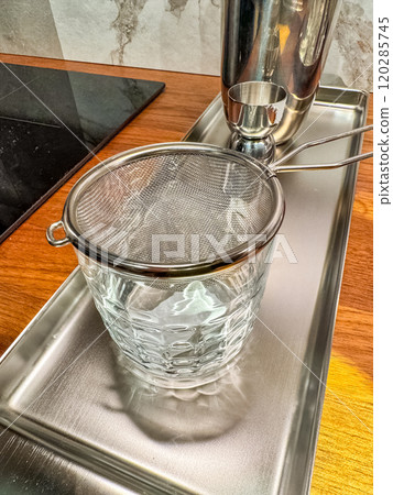 a small metal strainer on a glass of ice for making cocktail . High quality photo 120285745