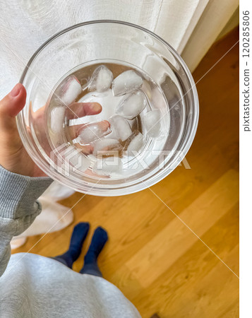 female hand holding the glass bowl with ice cubes, spa at home concept . High quality photo 120285806