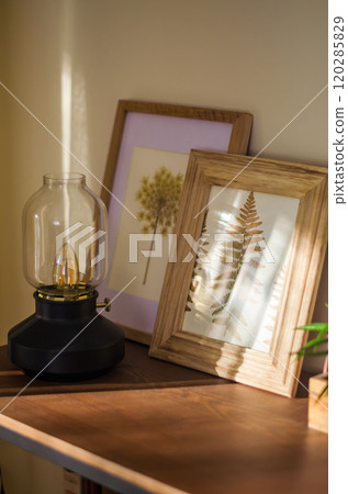 Cozy Interior Decor with Framed Art and Vintage Lamp in Warm Sunlight. High quality photo Cozy Interior Decor with Framed Art and Vintage Lamp in Warm Sunlight. High quality photo 120285829